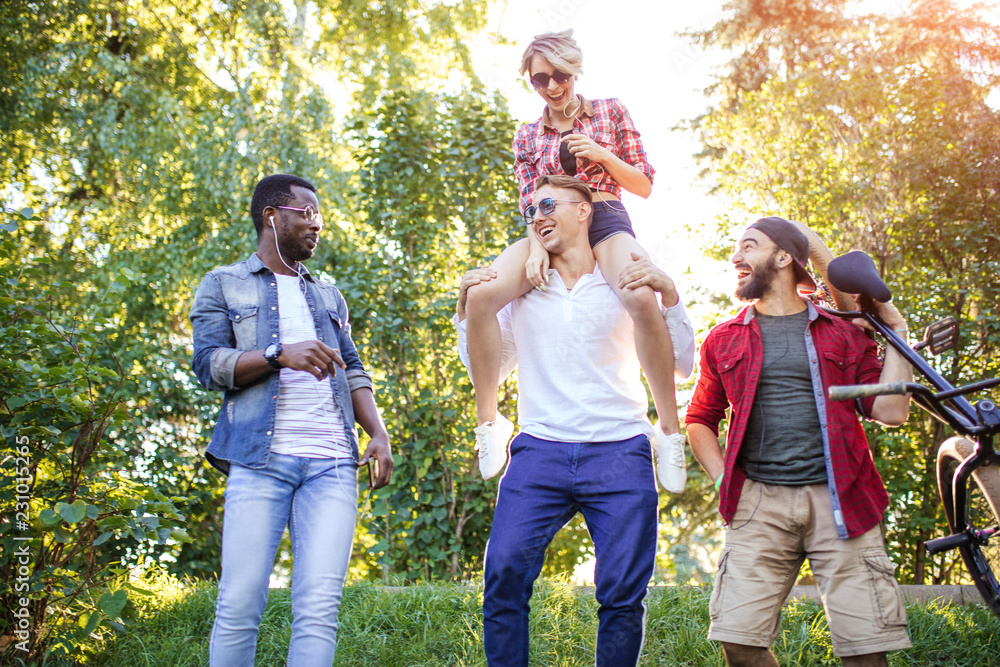 Fototapeta premium Happy adult guys and girls in casual wear enjoying a long walk excursion at the Botanical Garden.
