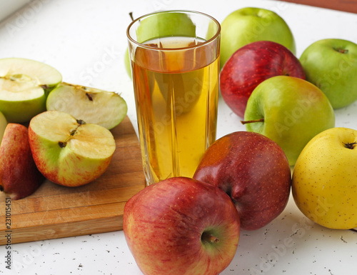  Apple juice in a glass and apples on the table.
