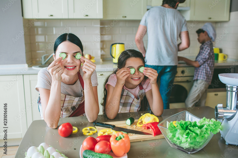 Funny girls are playing with food. They holds round pieces of cucumber where etes are and smile. Girls have a break. Biys are working at stove. They cook food. Funny girls are playing with food. They holds round pieces of cucumber where etes are and smile. Girls have a break. Biys are working at stove. They cook food.