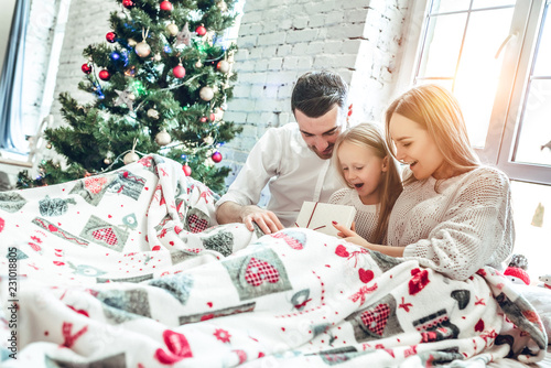 Family hugging near christmas tree on the bed. New year's morning
