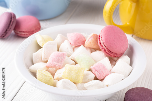 colorful candy and macaroons in a plate and on a table photo