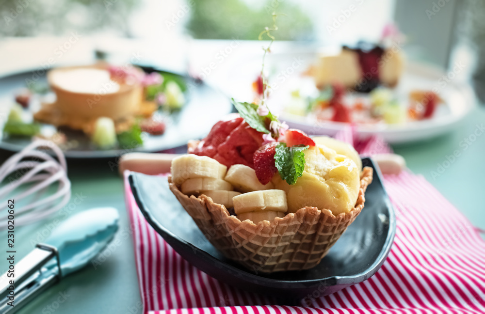 The fruit ice cream with banana,strawberry and mint leaf put in waffle basket,prepare for serving,blurry light around The fruit ice cream with banana,strawberry and mint leaf put in waffle basket,prepare for serving,blurry light around
