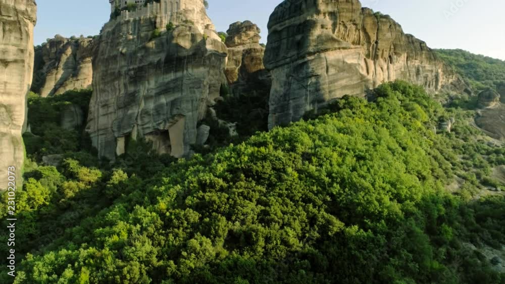 Aerial shot taking off over huge stone rock Meteora with monasteries complex on peak shooting from helicopter rising over amazing natural valley in Greece mountains and dense green forest at sunset Aerial shot taking off over huge stone rock Meteora with monasteries complex on peak shooting from helicopter rising over amazing natural valley in Greece mountains and dense green forest at sunset