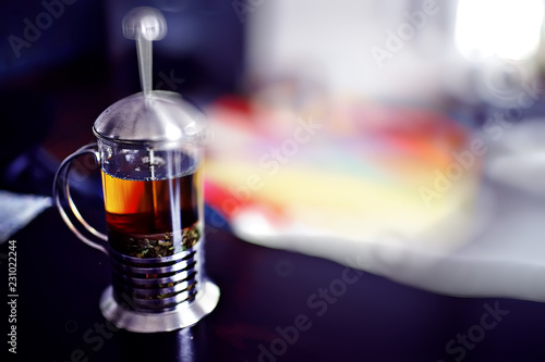 Indian tea / Indian tea concept in a glass teapot against a background of bright carpet in paints of holi, a national Indian drink