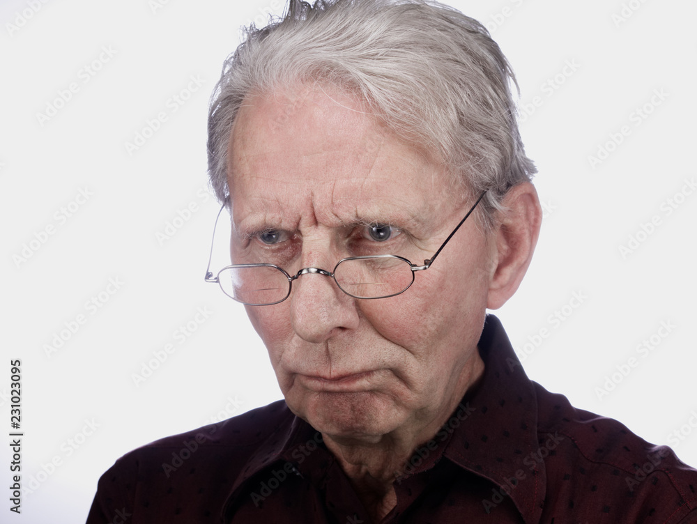 Alter Mann (79 J.) blickt mürrisch durch die Brille Alter Mann (79 J.) blickt mürrisch durch die Brille