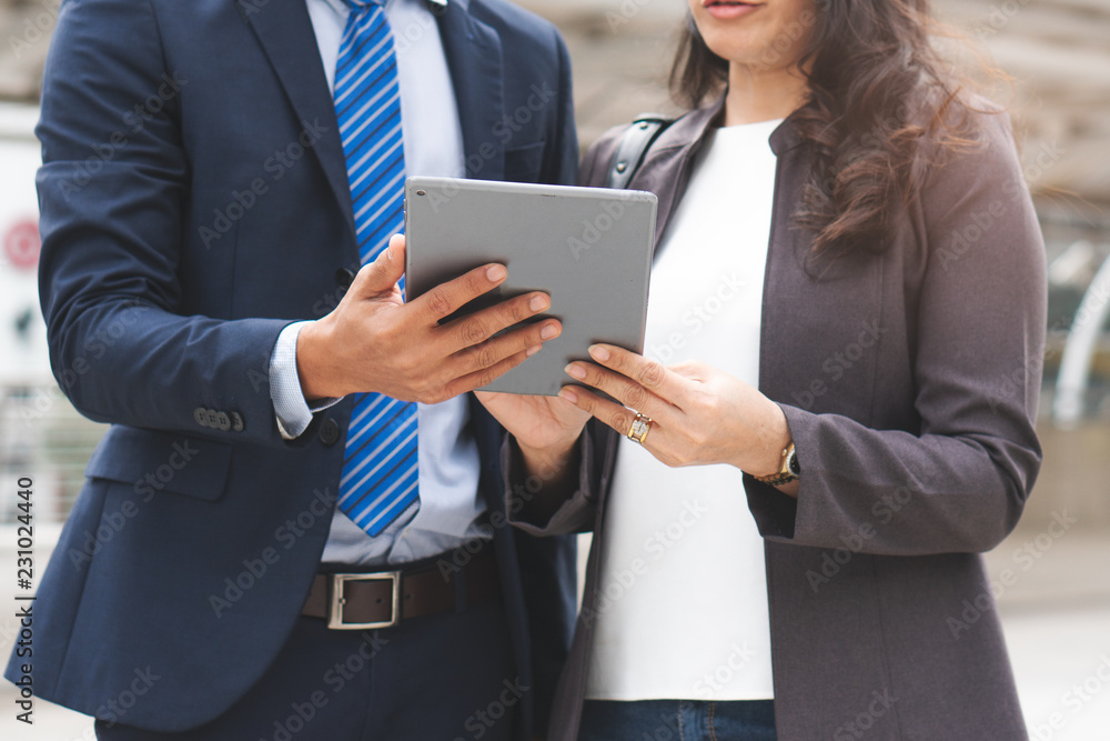 Happy Asian businessmen discussing with female boss in the city. Male open application in tablet showing data to present work. Happy Asian businessmen discussing with female boss in the city. Male open application in tablet showing data to present work.