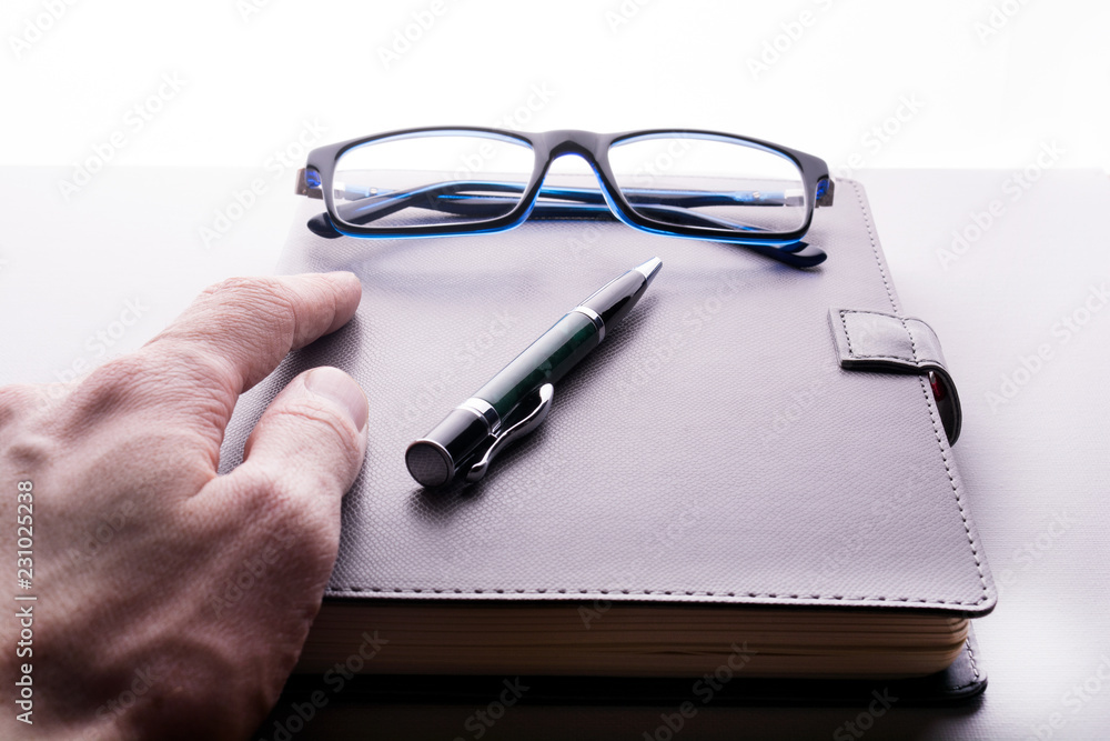 hand takes a notebook with glasses and a pen hand takes a notebook with glasses and a pen