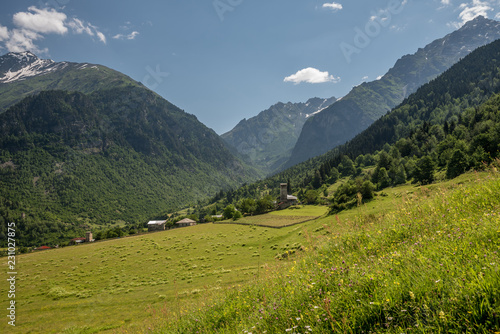 View of village Zhabeshi with traditional old stone towers surrounded by green meadows under high mountains Caucasus close to Mestia, Georgia