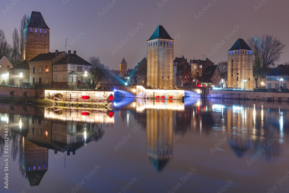 Medieval towers and bridges with mirror reflections in Petite France at night, Strasbourg, Alsace, France