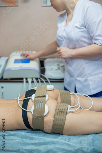 Lipo laser. A cosmetologist corrects the figure of a young woman with the help of the device. Body care. Non-surgical body sculpture. Formation of body contours, anti-cellulite and anti-fat therapy