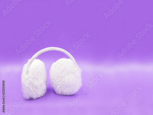 white winter headphones for the ears on purple background