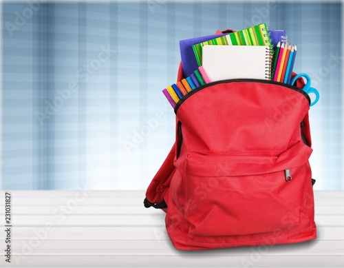 Colorful school supplies in backpack on wooden