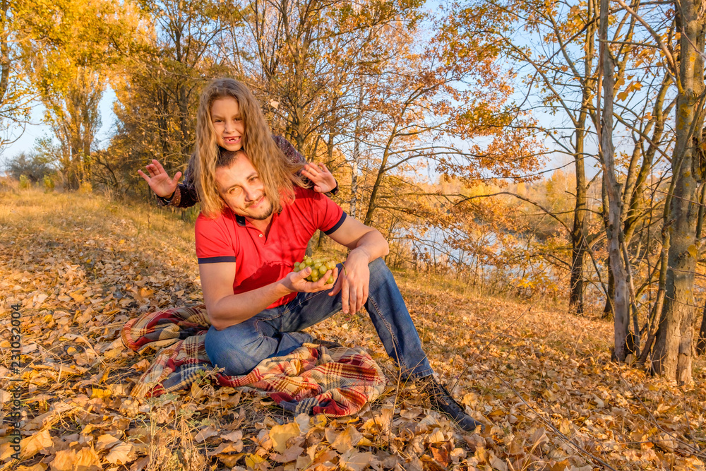 Father and his cute little daughter sitting on the fall leaves Father and his cute little daughter sitting on the fall leaves