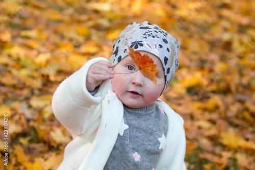 one little baby girl in the park with yellow leaves