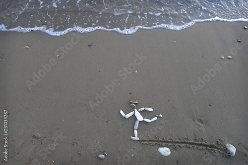 Figure Of Running Man Made Of Stones On Sand