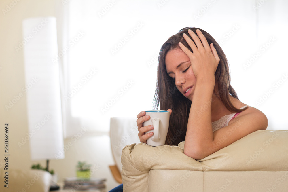 Young brunette girl depressed, sad with a cup of hot coffee or tea in the living room of her house with sadness, stress, desolate, lonely and helpless Young brunette girl depressed, sad with a cup of hot coffee or tea in the living room of her house with sadness, stress, desolate, lonely and helpless