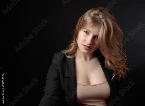 Portrait of beautiful woman with long curly blond hair on black background.