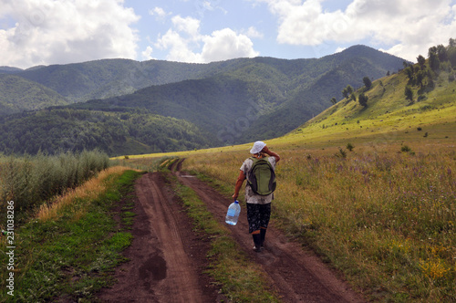 Woman walking on the road to beautiful green mountains