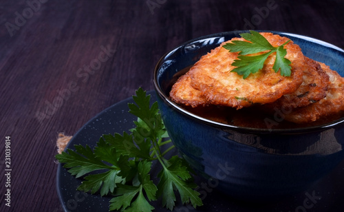 Vegetable pancakes topped with parsley leaves in a blue bowl photo