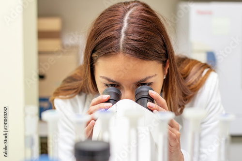 Girl in laborary looking at the microscope