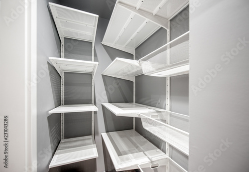 Empty wardrobe room with white metal shelves in the apartment