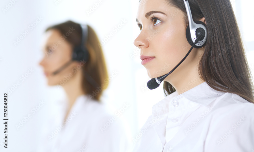 Group of call center operators at work. Focus at beautiful business woman in headset Group of call center operators at work. Focus at beautiful business woman in headset