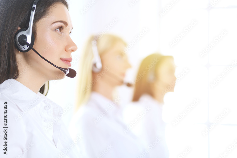 Group of call center operators at work. Focus at beautiful business woman in headset Group of call center operators at work. Focus at beautiful business woman in headset