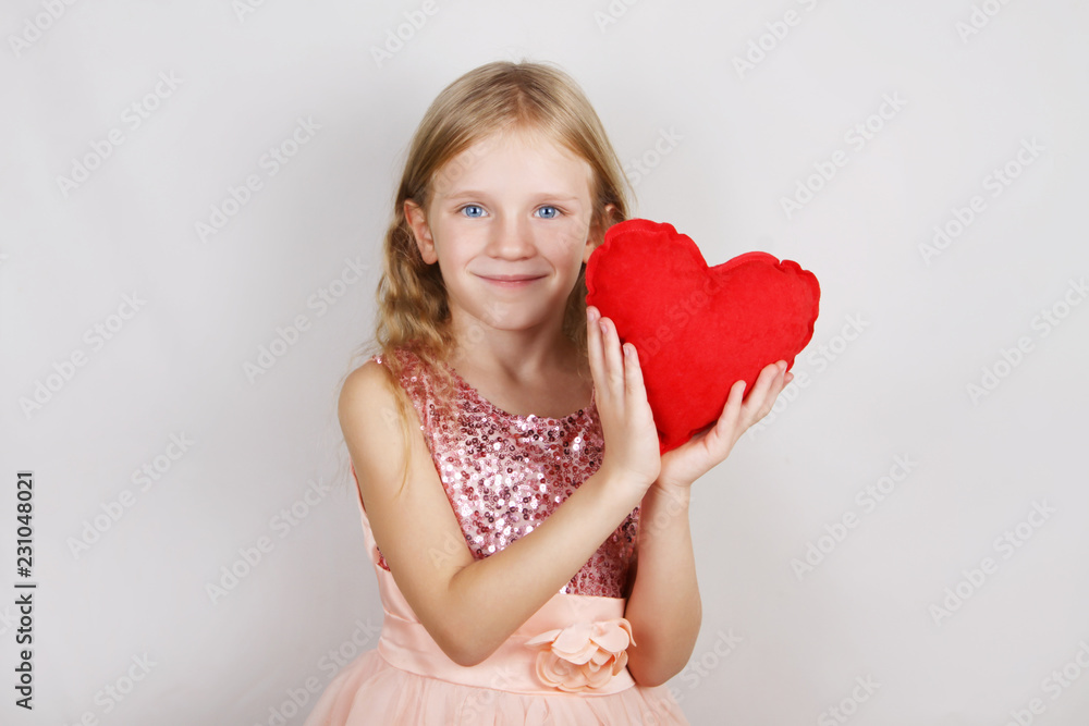 beautiful blond girl with red heart on a white background. Child with a heart for Valentine's day beautiful blond girl with red heart on a white background. Child with a heart for Valentine's day