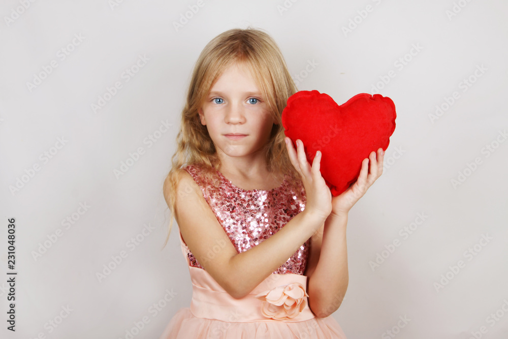 beautiful blond girl with red heart on a white background. Child with a heart for Valentine's day beautiful blond girl with red heart on a white background. Child with a heart for Valentine's day