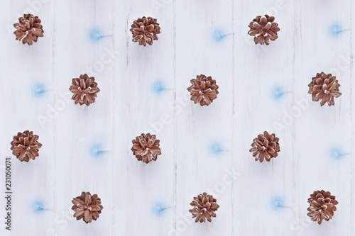 Seamless pattern of pine cones and glowing garland on a wooden surface. Christmas background and texture. Top view, flat lay