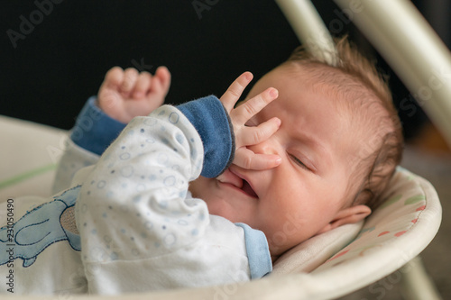 Obraz na płótnie Sleeping baby in swing automatic electrical chair and sucking left thumb