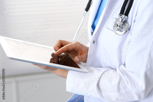 Woman doctor using white tablet computer while working in hospital, close-up