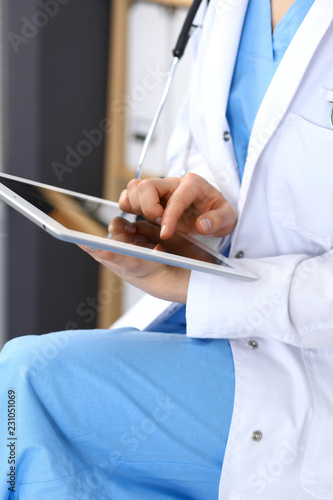 Woman doctor using white tablet computer while working in hospital, close-up