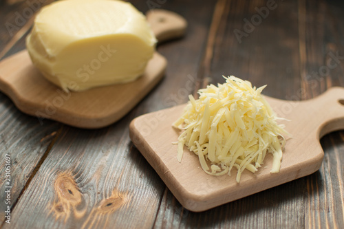 Grated cheese for cooking on a wooden background.