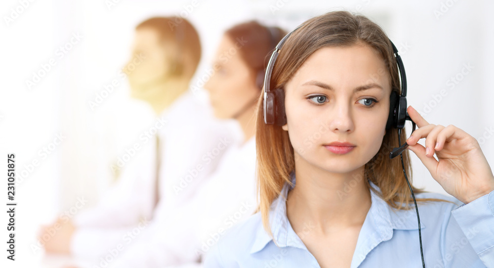 Call center operators. Focus on young cheerful smiling woman in headset. Business and customer service concepts Call center operators. Focus on young cheerful smiling woman in headset. Business and customer service concepts