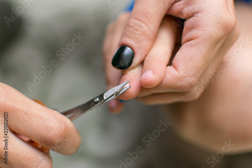 Cutting nails to a child. Female hands hold nail scissors and child s hand.