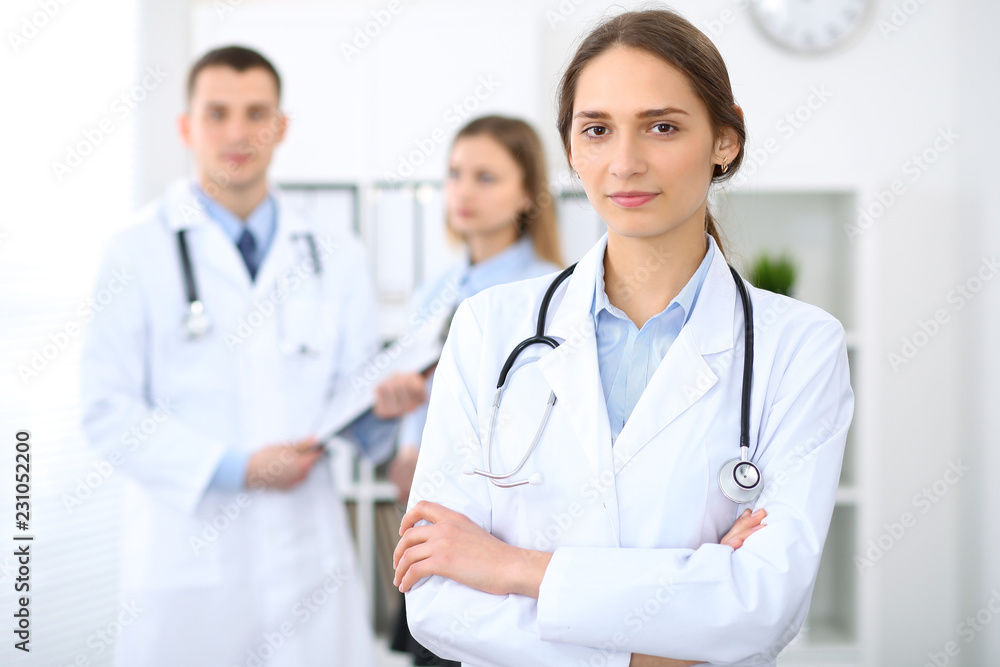 Young beautiful female doctor smiling on the background with patient in hospital Young beautiful female doctor smiling on the background with patient in hospital