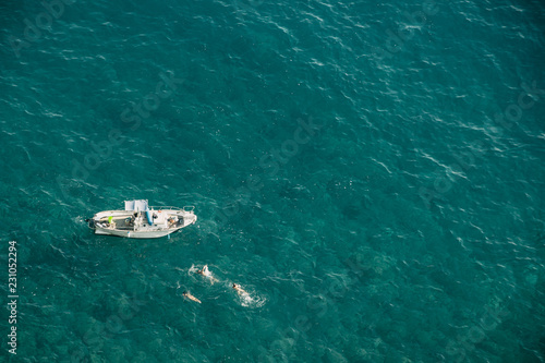 Aerial view on small boat on open waters with people swimming © FliNdt