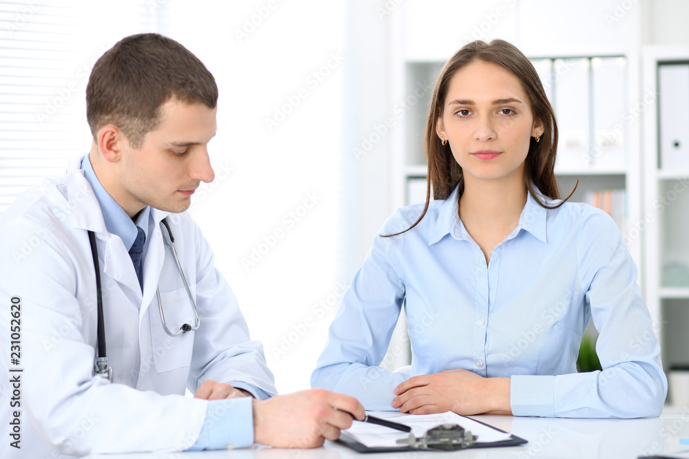 Friendly male doctor on the background with patient and physician Friendly male doctor on the background with patient and physician