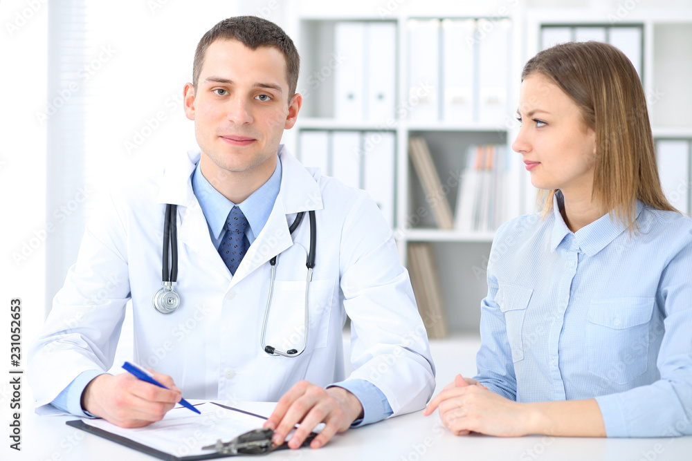 Doctor and patient sitting at the desk. Medicine and health care concept Doctor and patient sitting at the desk. Medicine and health care concept