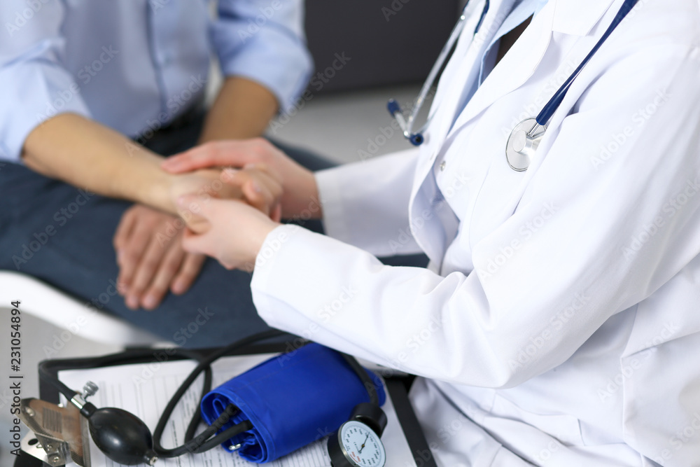 Female doctor checking blood pressure or pulse of the male patient, in hospital. Medicine and healthcare concept Female doctor checking blood pressure or pulse of the male patient, in hospital. Medicine and healthcare concept