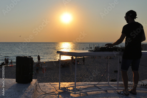 DJ plays music on the beach at sunset