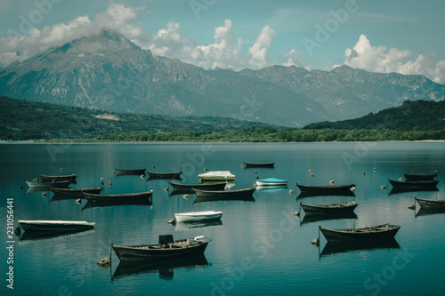 Calm boats on Lago di Santa Croce  Italy. Dolomites in background with clouds and sky.