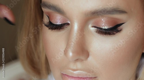 Make-up artist makes make-up eyelashes in a young woman