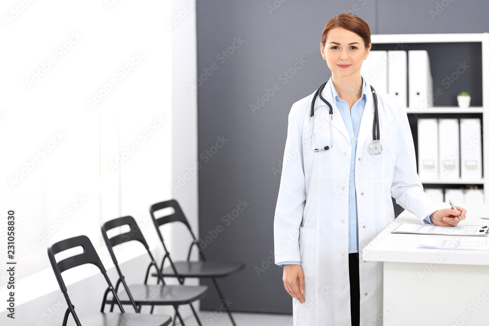 Doctor woman at work. Portrait of female physician filling up medical form while standing near reception desk at clinic or emergency hospital. Medicine concept Doctor woman at work. Portrait of female physician filling up medical form while standing near reception desk at clinic or emergency hospital. Medicine concept