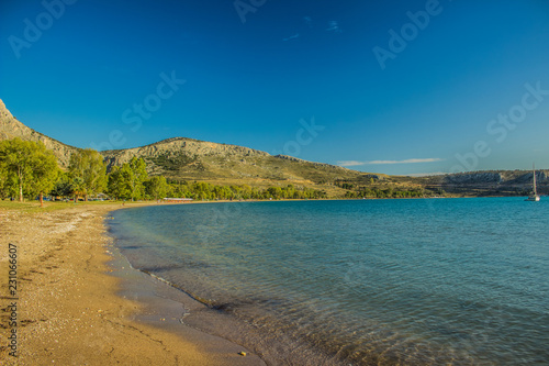 Mediterranean sea shore bay beautiful landscape with vivid water green and blue surface and rock horizon background in summer warm sultry weather
