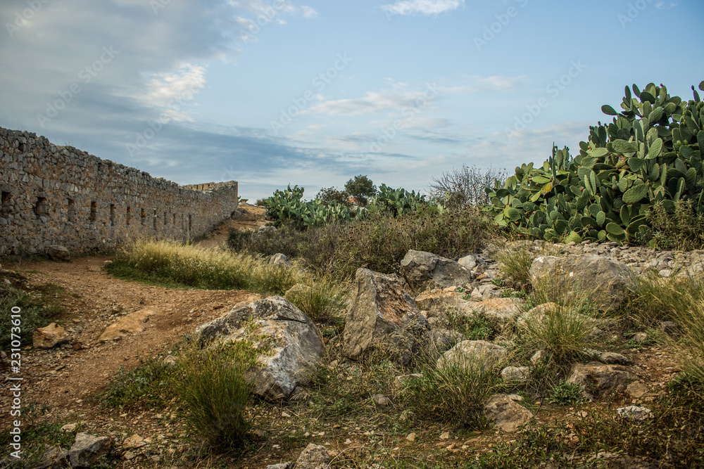 old ruins of south castle with destroyed stones walls and yard empty space with rocks and cacti
