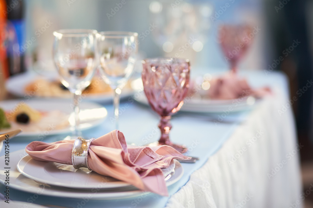 Wedding dinner service. Crystal glasses and porcelain plates served on the dinner table
