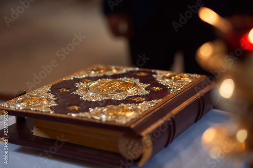 Bible in hard wooden cover with gold stands on the table in church