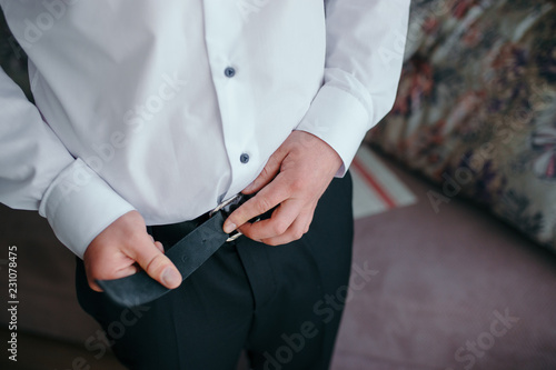 Grooms morning preparation, handsome groom getting dressed and preparing for the wedding, in dark blue suit.